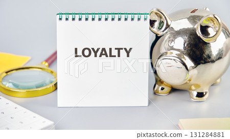 LOYALTY word written in a notebook in a composition with a piggy bank and a magnifying glass. Fake Dictionary, Dictionary definition concept. LOYALTY word written in a notebook in a composition with a piggy bank and a magnifying glass. Fake Dictionary, Dictionary definition concept. 131284881