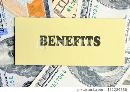 BENEFITS text written on yellow paper on the background of banknotes. Banking business, finance and investment concept. 131284886