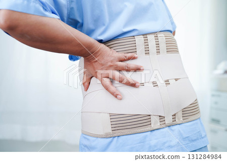 Asian senior pain back wearing elastic support belt with walker. 131284984