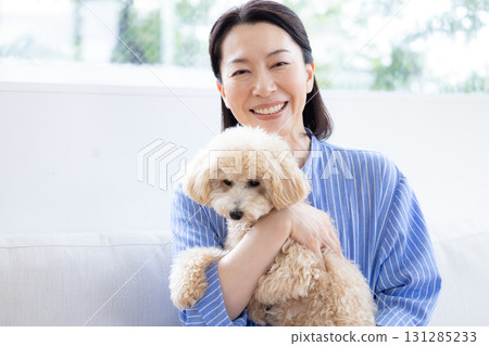 Lifestyle Living Room Middle-aged woman holding her pet dog 131285233