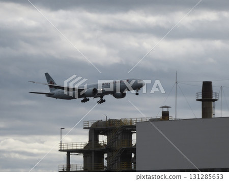 一架加拿大航空的波音 777 在陰雲密佈的天空下低空飛過一座工廠。 131285653