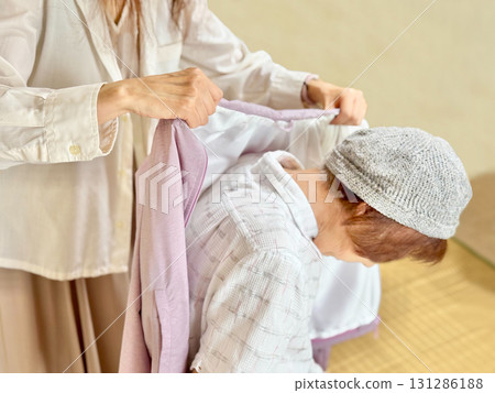 A woman's hand putting a jacket on an elderly woman_right facing A woman's hand putting a jacket on an elderly woman_right facing 131286188
