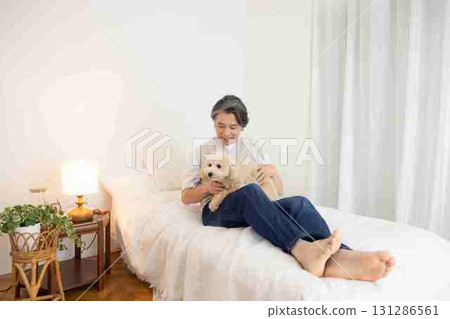 Pet: Dog relaxing on bed with owner 131286561