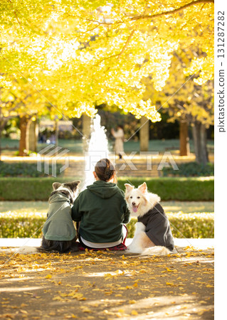 一個人和一隻邊境牧羊犬緊緊站在一起，凝視著噴泉 131287282