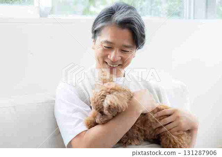 A middle-aged man playing with a toy poodle 131287906