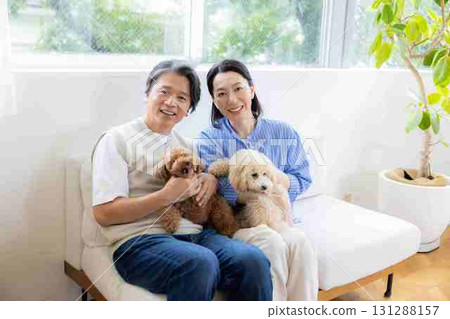 一對中年夫婦在客廳和他們的狗一起玩耍 131288157