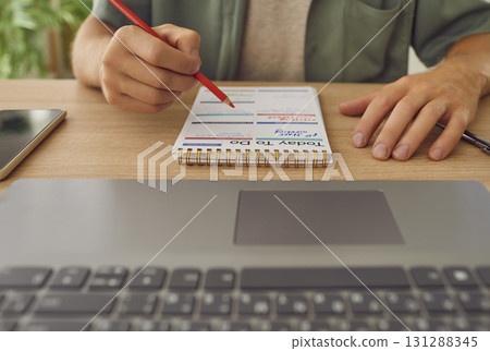 Man in office writes goals, plans, make to do and wish list in small notebook. Man in office writes goals, plans, make to do and wish list in small notebook. 131288345