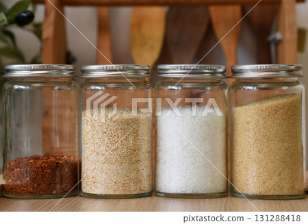 A clear jar that holds seasonings for cooking inside. On the wooden table in the kitchen A clear jar that holds seasonings for cooking inside. On the wooden table in the kitchen 131288418