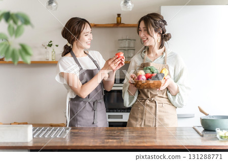 繫著圍裙的年輕亞洲女子在廚房裡拿著蔬菜（烹飪課、烹飪學校） 131288771