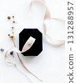 Elegant engagement ring in a velvet box, adorned with ribbon & flowers on white. 131288957