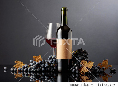 Bottle of red wine with blue grapes on a black reflective background. 131289516