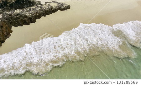 Tranquil tropical beach scene from above, featuring waves meeting golden sand. Tranquil tropical beach scene from above, featuring waves meeting golden sand. 131289569