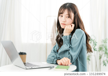 一位年輕的亞洲女商人，看著電腦時感到沮喪、思考和擔憂（沮喪、孤獨） 131289974