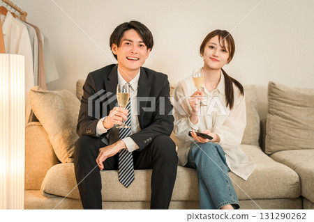 Young Asian couple drinking champagne while sitting on the sofa after returning home at night 131290262