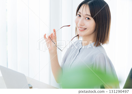 一位戴著眼鏡坐在電腦前的年輕女子 131290497