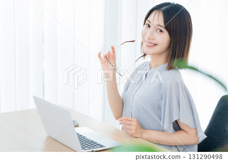 A young woman wearing glasses in front of a computer A young woman wearing glasses in front of a computer 131290498