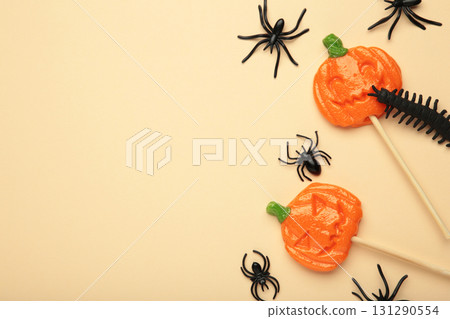 Halloween lollipops shaped like a pumpkin with decorative spider on beige background. Halloween lollipops shaped like a pumpkin with decorative spider on beige background. 131290554