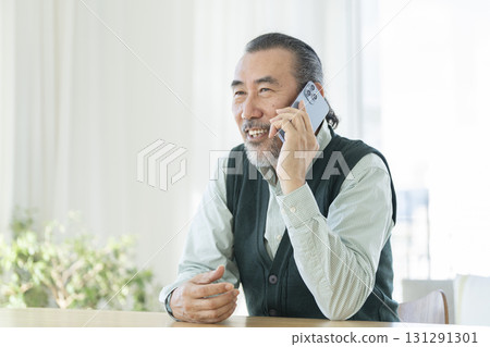 一位 70 多歲的男子麵帶微笑,正在用智慧型手機聊天 一位 70 多歲的男子麵帶微笑,正在用智慧型手機聊天 131291301