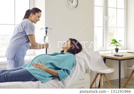 Doctor or nurse assistant put dropper on pregnant woman to improve her health and her future child. Doctor or nurse assistant put dropper on pregnant woman to improve her health and her future child. 131291966