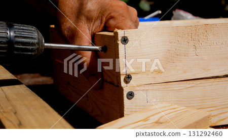 The master tightens the screw with a screwdriver during the manufacture of a wooden box. 131292460