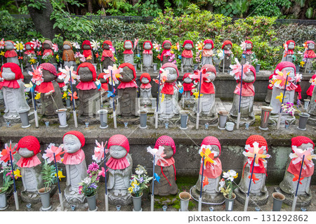 Jizo statues wearing red hats and bibs at Japanese temple garden with flowers at Tokyo, Japan 131292862