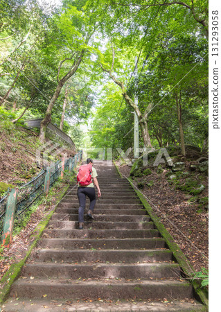Woman hiking up stone stairs in green forest trail with red backpack at Oyama mountain, Isehara, Kanagawa, Japan 131293058