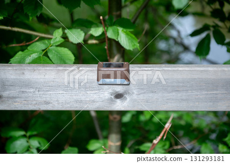 Small outdoor solar lamp on wooden railing in nature Small outdoor solar lamp on wooden railing in nature 131293181