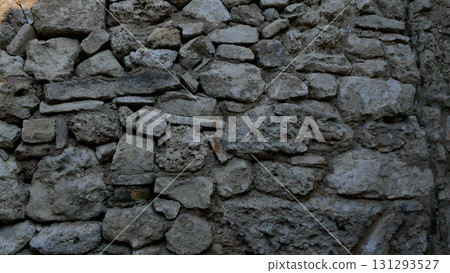 An ancient stone wall made up of gray stones of different sizes.  131293527