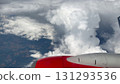 Wing of an airplane above white fluffy clouds in the blue sky. 131293536