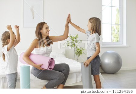 Family joyful home fitness, yogi mother and sporty kids giving high five in excitement, happy Family joyful home fitness, yogi mother and sporty kids giving high five in excitement, happy 131294196