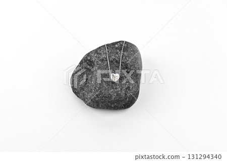 A heart shaped diamond pendant is sitting on a rock 131294340