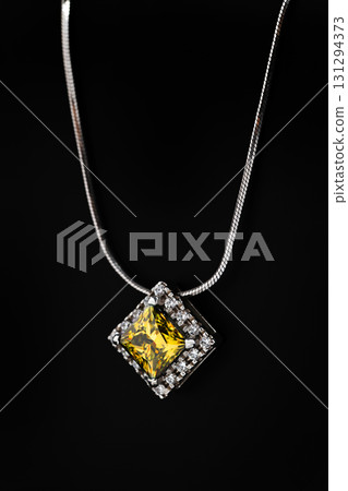 A yellow diamond necklace sits on a black surface 131294373