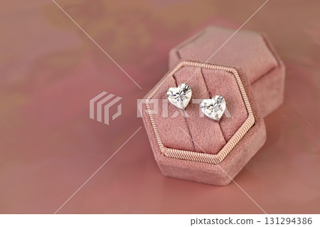 A pair of diamond earrings are displayed in a pink velvet box A pair of diamond earrings are displayed in a pink velvet box 131294386