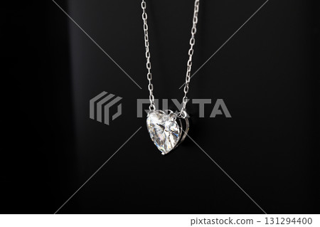 A necklace with a heart pendant is on a black record 131294400