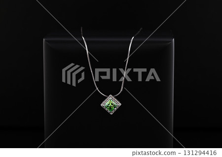 A green gemstone pendant is displayed on a black background A green gemstone pendant is displayed on a black background 131294416