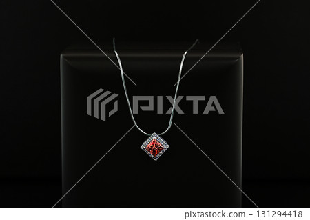 A silver necklace with a red gemstone pendant 131294418