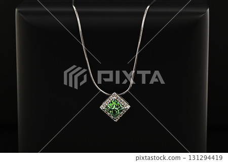 A green gemstone pendant is displayed on a black background A green gemstone pendant is displayed on a black background 131294419