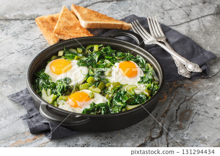 green shakshuka is healthy, one-pan and full of fresh herbs, spinach, and eggs closeup on the pan. Horizontal green shakshuka is healthy, one-pan and full of fresh herbs, spinach, and eggs closeup on the pan. Horizontal 131294434
