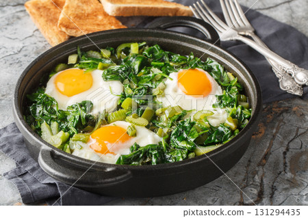 Green shakshuka is a stew of eggs in a mixture of green vegetables and herbs, close-up in a frying pan. Horizontal Green shakshuka is a stew of eggs in a mixture of green vegetables and herbs, close-up in a frying pan. Horizontal 131294435
