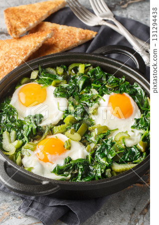 shakshuka green sauce loaded with fresh herbs, spinach, and spices is the perfect foil for rich, runny eggs closeup on the pan. Vertical shakshuka green sauce loaded with fresh herbs, spinach, and spices is the perfect foil for rich, runny eggs closeup on the pan. Vertical 131294438