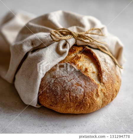 Artisan sourdough bread wrapped in cloth and twine, isolated on white background with rustic charm 131294778