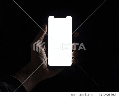 Hand holding a white smartphone that glows in the dark Hand holding a white smartphone that glows in the dark 131296168