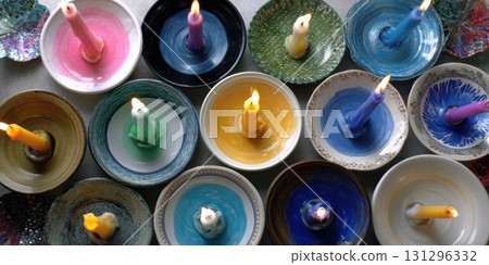 DIY candle plate using mismatched holders with bright taper candles and colorful wax puddles in cozy lighting 131296332