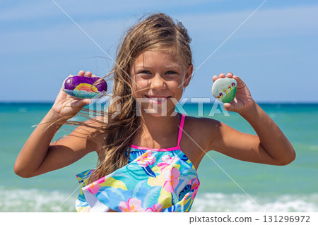 Happy Child Displaying Colorfully Painted Stones at the Beach Happy Child Displaying Colorfully Painted Stones at the Beach 131296972