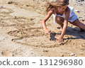 Little girl drawing hopscotch in the sand on a sunny beach 131296980
