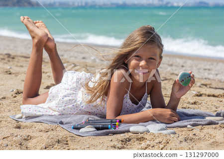 Smiling Child Showing Painted Stone on Beach 131297000