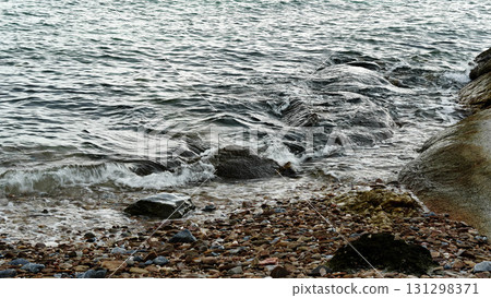 Seawater waves hitting coastal rocks. 131298371