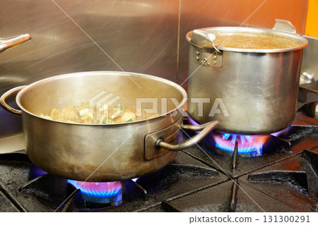 Restaurant pro kitchen with steel pans in fire 131300291
