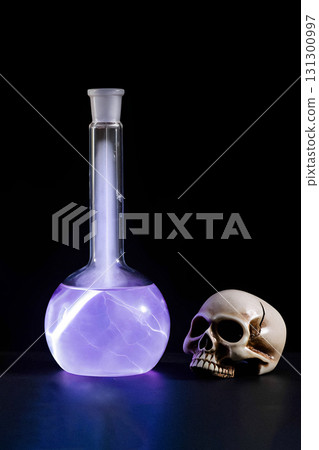 Alchemistry symbols. Human skull and a flask with glowing purple plasma on black background, vertical image. Alchemistry symbols. Human skull and a flask with glowing purple plasma on black background, vertical image. 131300997