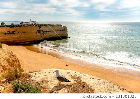 Stunning image of Algarve iconic cliffs of Seven Hanging Valleys and golden sandy beach. Serene shoreline, set against the clear blue ocean, capturing Portugal natural beauty 131301323